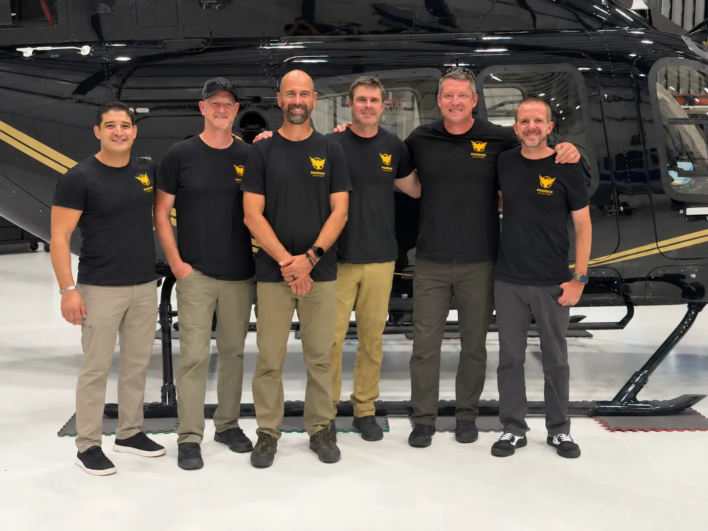 Phoenix Aviation team beside a helicopter in the hangar